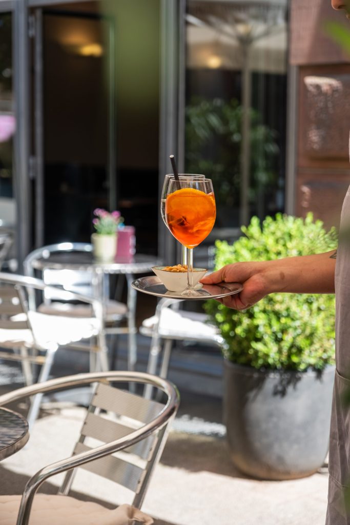 Terrasse des Café Rih mit Bistrostühlen vor historischer Fassade