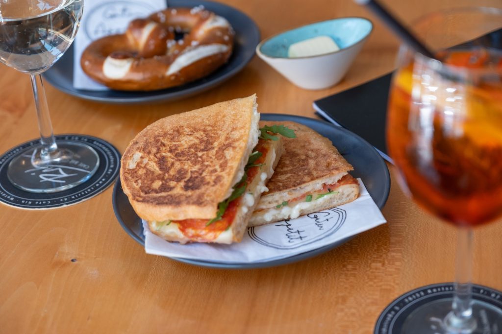 Getoastetes Sandwich mit Tomate und Rucola, Brezel und Aperitivo im Café Rih